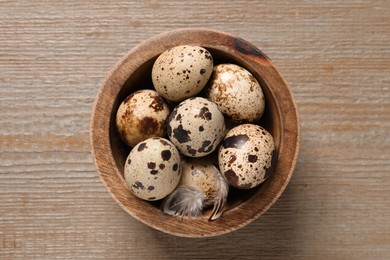 Bowl with quail eggs on wooden table, top view