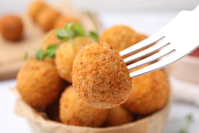 Photo of Taking delicious fried tofu ball with fork from bowl, closeup
