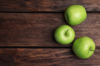 Fresh ripe green apples on wooden table, flat lay. Space for text