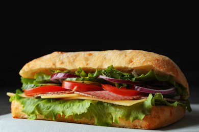 Photo of Delicious sandwich with fresh vegetables and salami on table