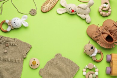 Photo of Frame of baby clothes and accessories on light green background, flat lay. Space for text