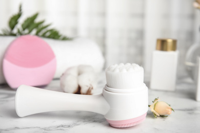 Modern face cleansing brush on marble table. Cosmetic accessory