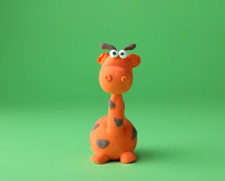 Photo of Small giraffe made from play dough on green background