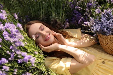 Young woman lying in lavender field on summer day