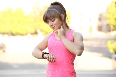 Photo of Young woman checking pulse after workout in park