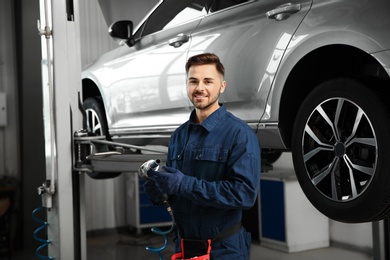 Technician with tool in automobile repair shop