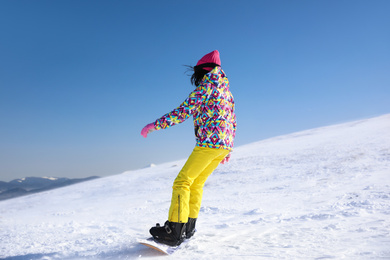 Young woman snowboarding on hill. Winter vacation