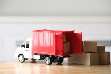 Toy truck and cardboard boxes on table against blurred background. Courier service
