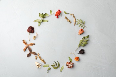 Dried flowers, leaves and berries arranged in shape of wreath on light grey background, flat lay with space for text. Autumnal aesthetic