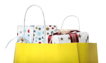 Photo of Yellow paper shopping bag full of gift boxes on white background, closeup