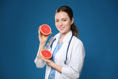 Nutritionist with ripe grapefruit on blue background