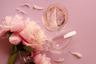 Flat lay composition with rose wine, glasses and beautiful peonies on pink background