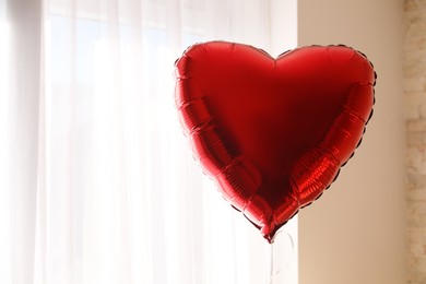 Photo of Red heart shaped balloon indoors, space for text
