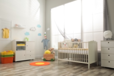 Photo of Blurred view of baby room with stylish furniture