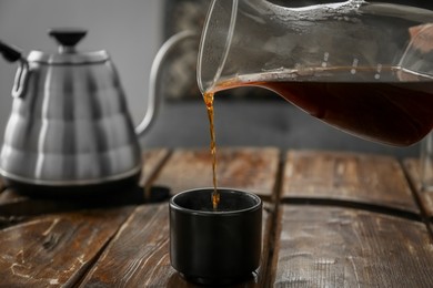 Photo of Pouring coffee into cup at wooden table in cafe