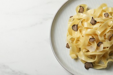Delicious pasta with truffle slices on white table, top view. Space for text