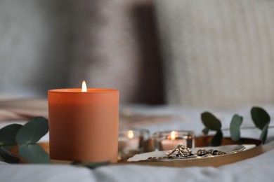 Tray with beautiful candles and eucalyptus on bed, space for text
