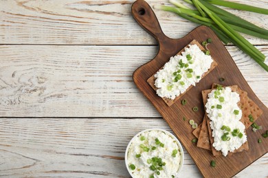 Photo of Crispy crackers with cottage cheese and green onion on white wooden table, flat lay. Space for text