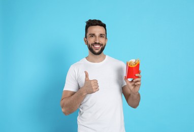 Man with French fries on light blue background