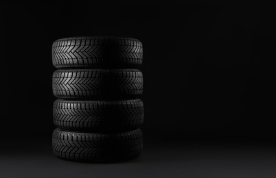 Winter tires on black background. Space for text