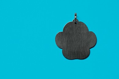 Silver pet tag with ring on light blue background, top view. Space for text