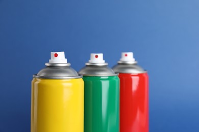 Colorful cans of spray paints on blue background