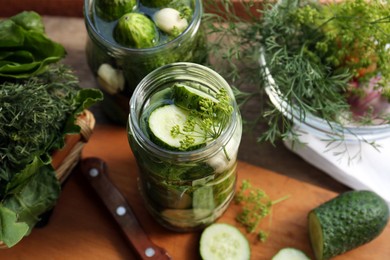 Photo of Glass jars, fresh cucumbers and herbs on wooden table. Pickling recipe