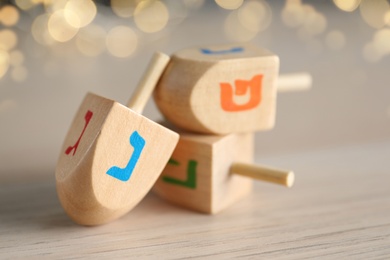 Hanukkah traditional dreidel with letters Nun and Gimel on wooden table, closeup