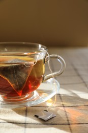 Photo of Tea bag in glass cup on table, closeup