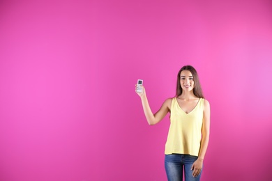 Photo of Young woman switching on air conditioner on color background