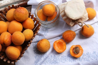 Jars and fresh ripe apricots on white tablecloth. Fruit preserve