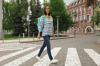 Young woman crossing street. Traffic rules and regulations