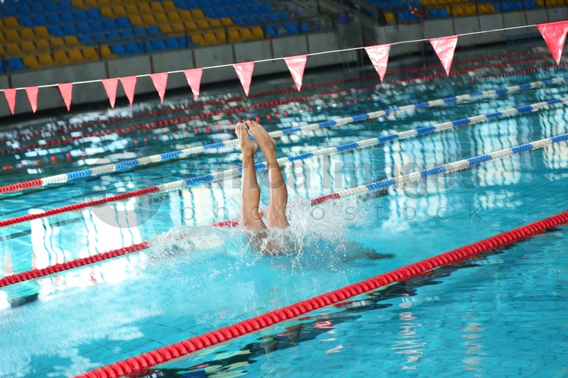 Young athletic man jumping into swimming pool