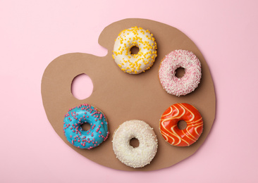 Artist's palette made with donuts and cardboard on pink background, top view
