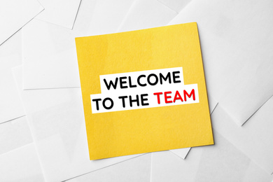 Note with phrase Welcome to the team on sheets of paper, top view