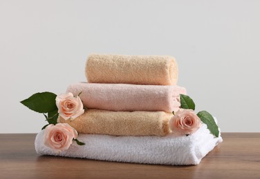 Stack of folded colorful towels with roses on wooden table