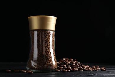 Photo of Glass jar with aromatic instant coffee and beans on black wooden table. Space for text