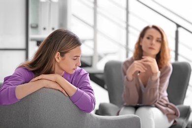Child psychologist working with teenage girl in office