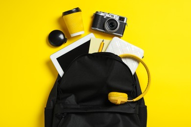 Stylish urban backpack with different items on yellow background, flat lay