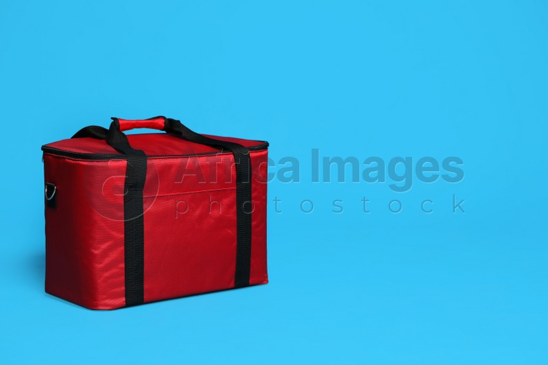Modern red thermo bag on light blue background. Space for text
