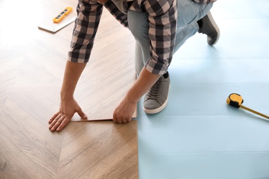 Worker installing laminated wooden floor indoors, closeup