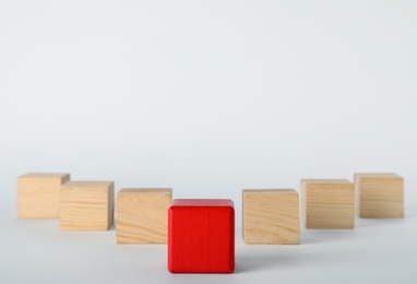 Red cube in front of wooden ones on white background. Victory concept
