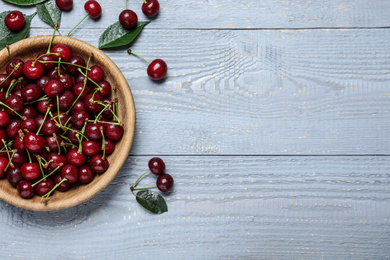 Sweet juicy cherries on blue wooden table, flat lay. Space for text