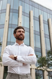 Photo of Portrait of handsome bearded man on city street, low angle view. Space for text