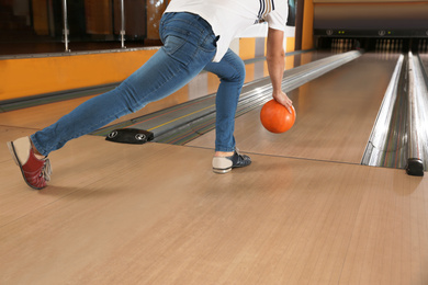 Young man throwing ball in bowling club, closeup