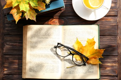 Maple leaves, book and glasses on wooden table, flat lay. Autumn atmosphere