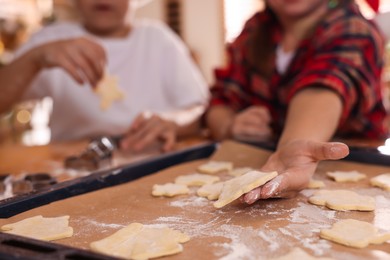 Cute little children making delicious Christmas cookies at home, closeup