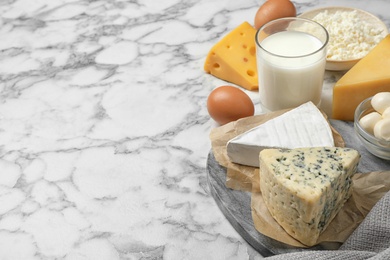 Photo of Different dairy products on marble table. Space for text