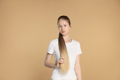 Teenage girl with strong healthy hair on beige background