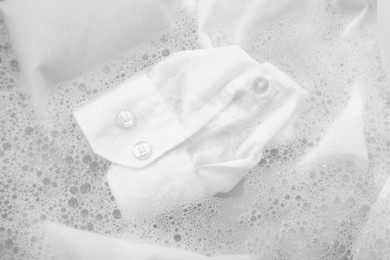 Photo of White garment in suds, closeup. Hand washing laundry
